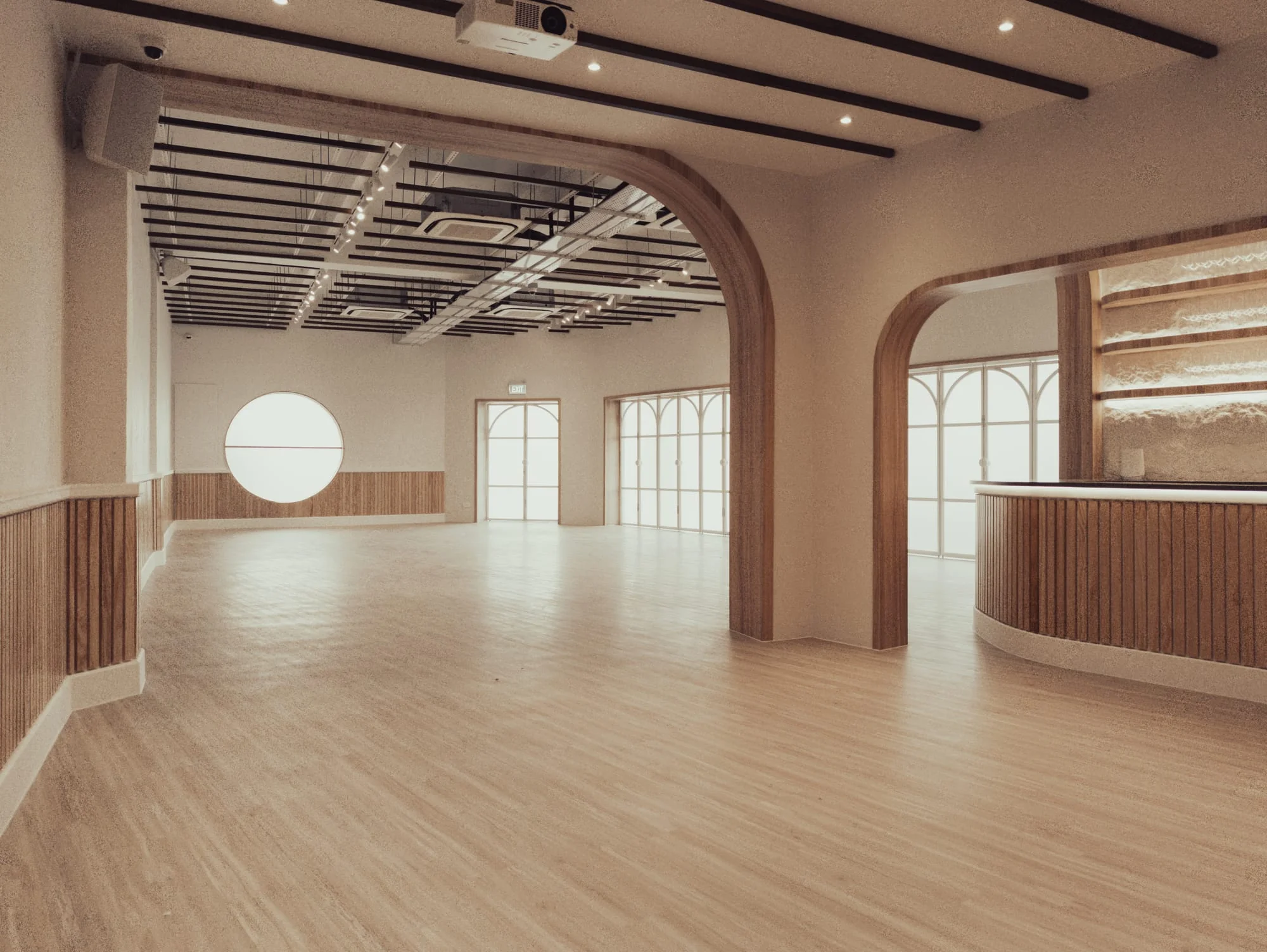 Grand view of Haus217's main hall through a large archway, showing the open floor area with the circular window, arched glass doors, and warm ambient lighting